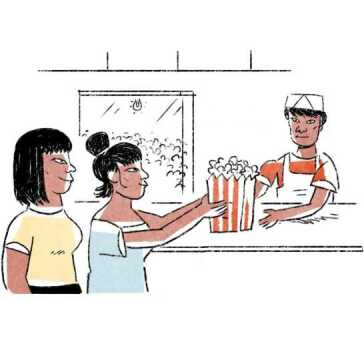 Two women buying a bucket of popcorn.