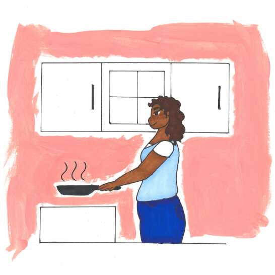 Uma mulher de pé, segurando uma frigideira.